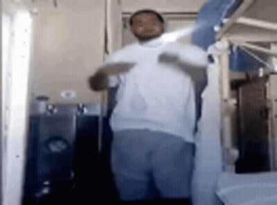 Man In White Shirt Holding Shirt Up In Bathroom GIF