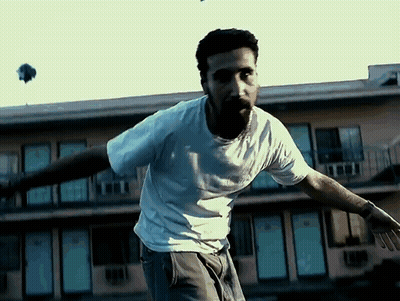 Man In White Shirt In Front Of Building With Blue Doors GIF