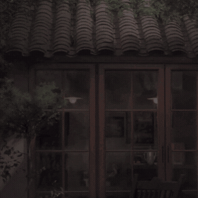 Man In White Shirt In Front Of Building With Tiled Roof GIF