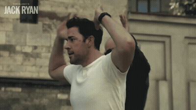 Man In White Shirt In Front Of Jack Ryan Wall GIF