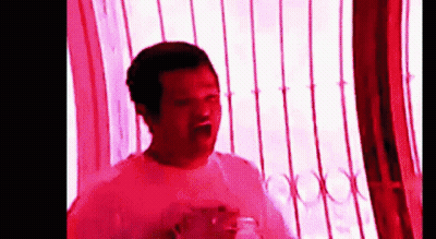 Man In White Shirt In Front Of Window With Red Light GIF