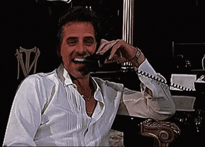 Man In White Shirt Laughing And Talking On Phone GIF