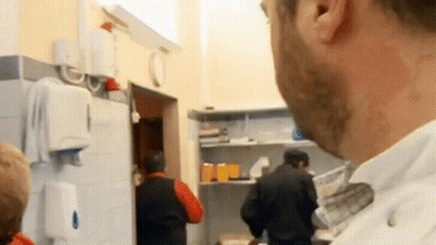 Man in White Shirt Looking at People in Kitchen