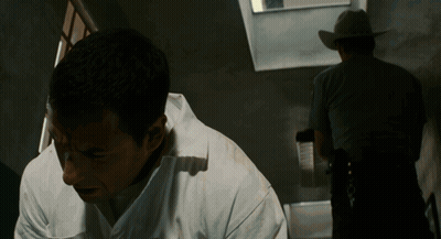 Man In White Shirt Looking Down With Cowboy Behind GIF