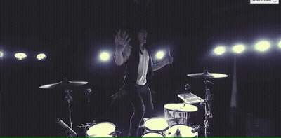 Man In White Shirt Playing Drum Set On Stage GIF