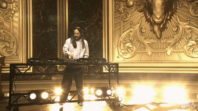 Man In White Shirt Playing Music In Front Of Gold Wall GIF