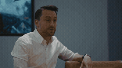 Man In White Shirt Sits On Couch In Front Of Picture GIF