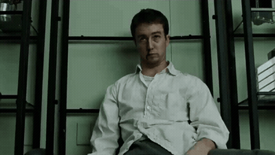 Man In White Shirt Sitting At Bookshelf GIF