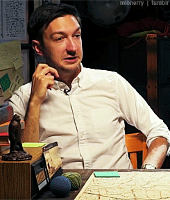 Man In White Shirt Sitting At Table With Map And Monkey Statue GIF