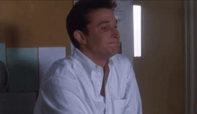 Man In White Shirt Sitting In Front Of Wall GIF