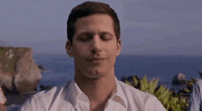Man In White Shirt Sitting On Beach Eyes Closed Smiling GIF