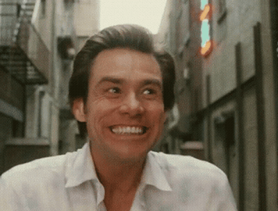 Man In White Shirt Smiling By Sign A In Alley GIF