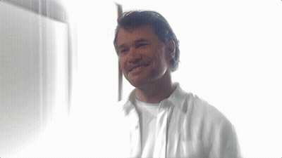Man In White Shirt Smiling In Front Of Window GIF