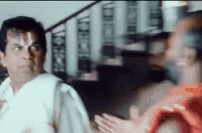 Man In White Shirt Standing Beside Man In Orange Shirt GIF