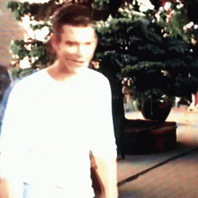 Man In White Shirt Standing In Front Of Christmas Tree GIF