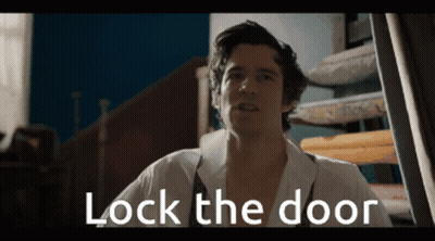 Man In White Shirt Standing In Front Of Door Saying Lock The Door GIF