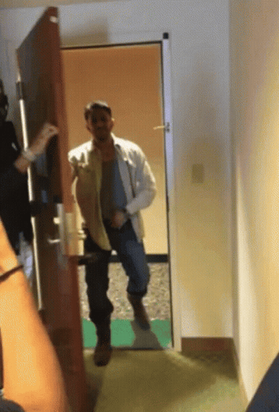 Man In White Shirt Standing In Hallway GIF
