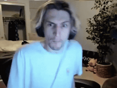 Man In White Shirt Standing In Room With Plant And Chair GIF