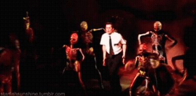 Man In White Shirt Surrounded By Dancing Skeletons GIF