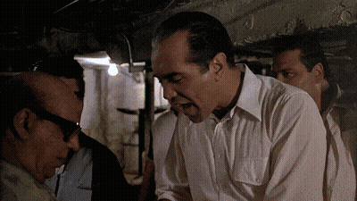 Man In White Shirt Talking To Another In Dark Room GIF