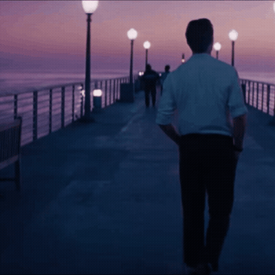 Man In White Shirt Walking Down Pier At Night GIF