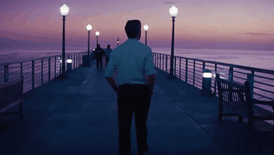 Man In White Shirt Walking Down Pier At Night GIF