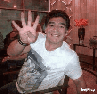 Man In White Shirt Waving While Sitting GIF