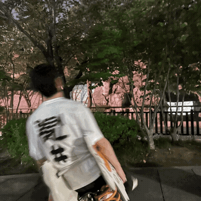 Man In White Shirt With Chinese Writing Walking Down Sidewalk GIF