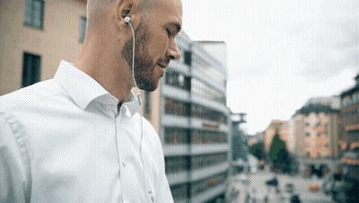 Man In White Shirt With Earbuds Looking Down GIF