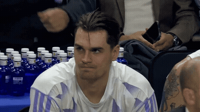 Man In White Shirt With Purple Stripes Sitting At Table Full Of Water Bottles GIF