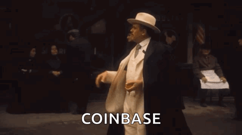 Man In White Suit And Hat Holding Orange Says Coinbase GIF