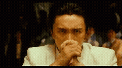 Man In White Suit Covering Mouth In Dark Room GIF