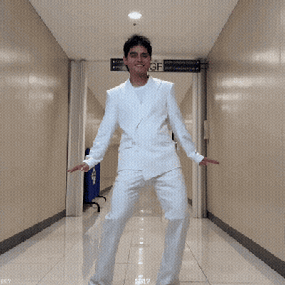 Man in White Suit Dancing Under GF Sign