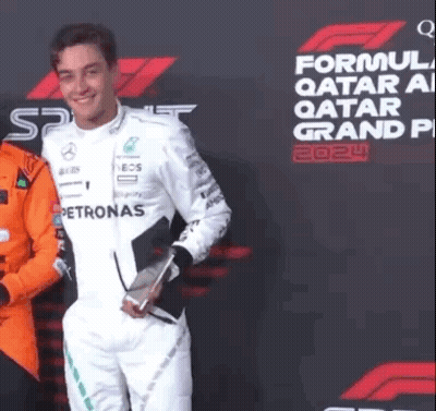 Man In White Suit In Front Of Formula One Qatar Grand Prix Sign GIF