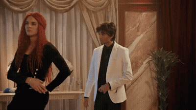 Man In White Suit Next To Woman With Red Hair GIF