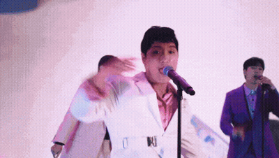 Man In White Suit Singing Into Microphone With Man In Purple Suit GIF