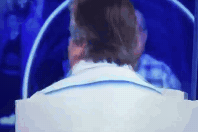 Man In White Suit Sitting In Front Of Screen GIF