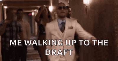 Man In White Suit Walking Up Hallway With People GIF