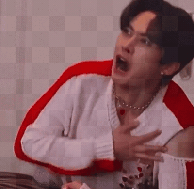 Man In White Sweater Making Face In Red Chair GIF