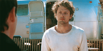 Man In White Sweater Standing In Front Of Trailer GIF