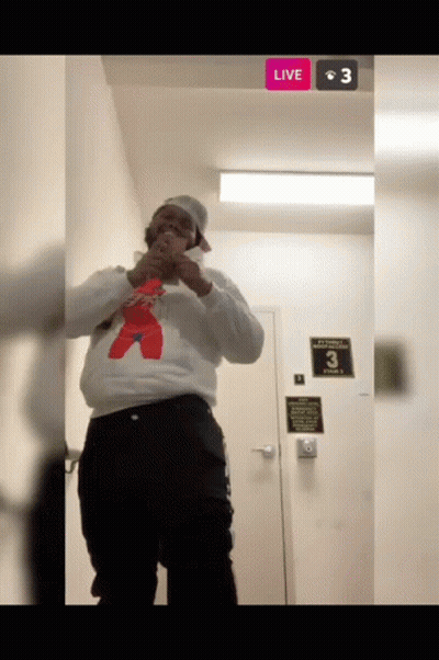 Man In White Sweatshirt And Red Bear At Door With Live Button GIF