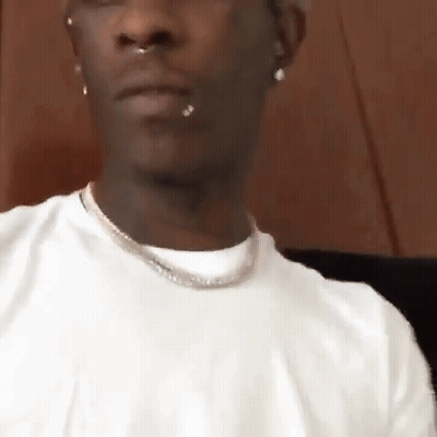 Man In White T-Shirt And Necklace Sitting Down GIF