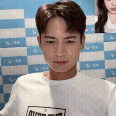 Man In White T-Shirt Black Logo Staring Camera GIF