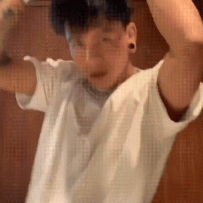 Man In White T-Shirt In Front Of Wooden Wall GIF