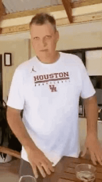 Man In White T-Shirt Saying Houston Standing At Table GIF