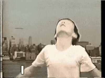 Man In White T-Shirt With Arms Outstretched City Skyline GIF