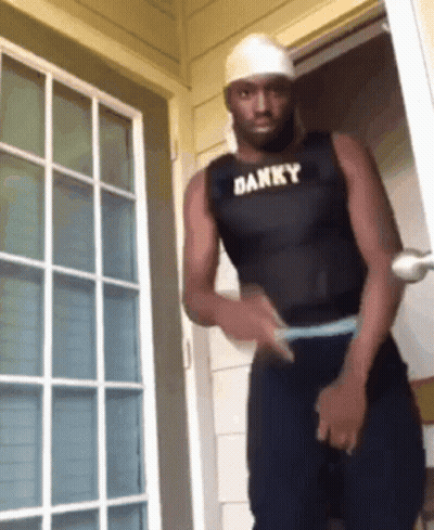 Man In White Tank Top Covering Face With Black Gloves GIF