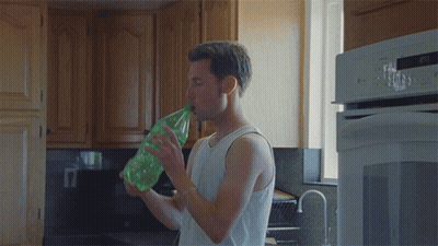 Man In White Tank Top Drinking From Green Bottle GIF