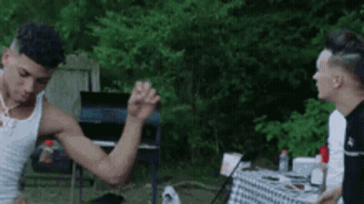 Man In White Tank Top Flexing Muscles At Table GIF