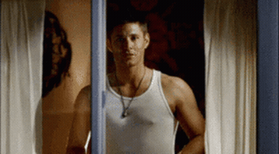 Man In White Tank Top Looking Out Window GIF